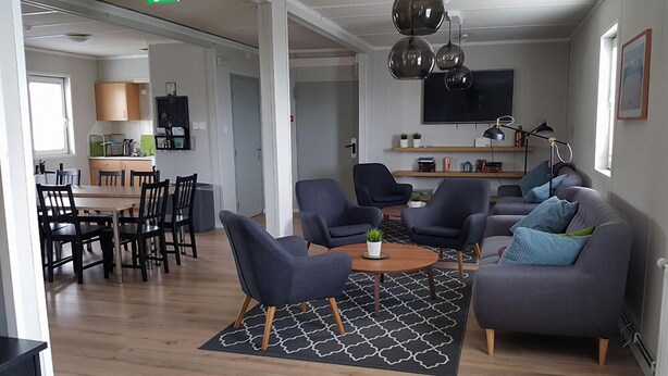 Un salon moderne avec un coin repas, comprenant un ensemble de canapés, des fauteuils, une table basse et un téléviseur.