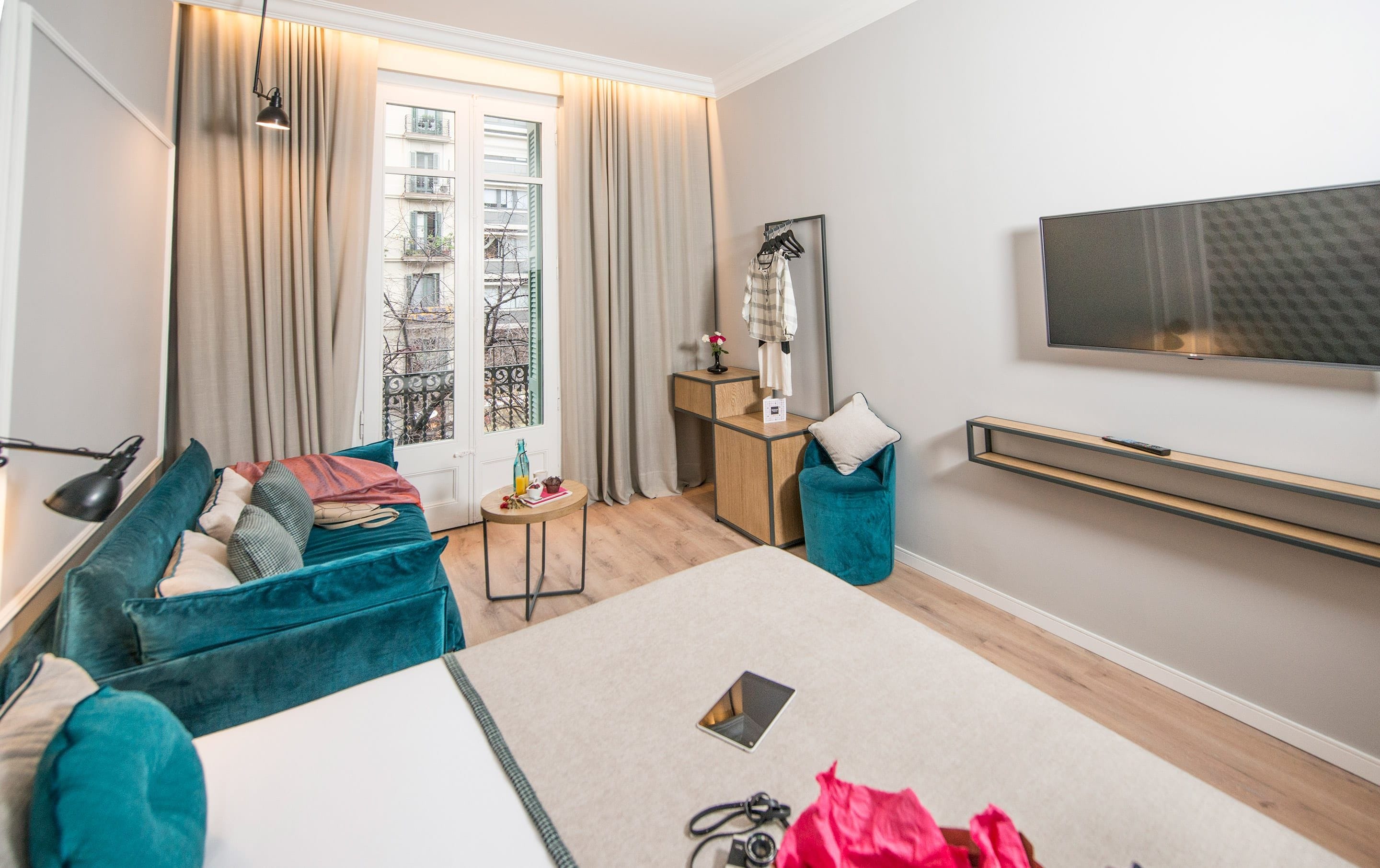 Une chambre d’hôtel moderne équipée d’un lit, d’un bureau, d’une chaise, d’une télévision et offrant une vue sur la ville par la fenêtre.