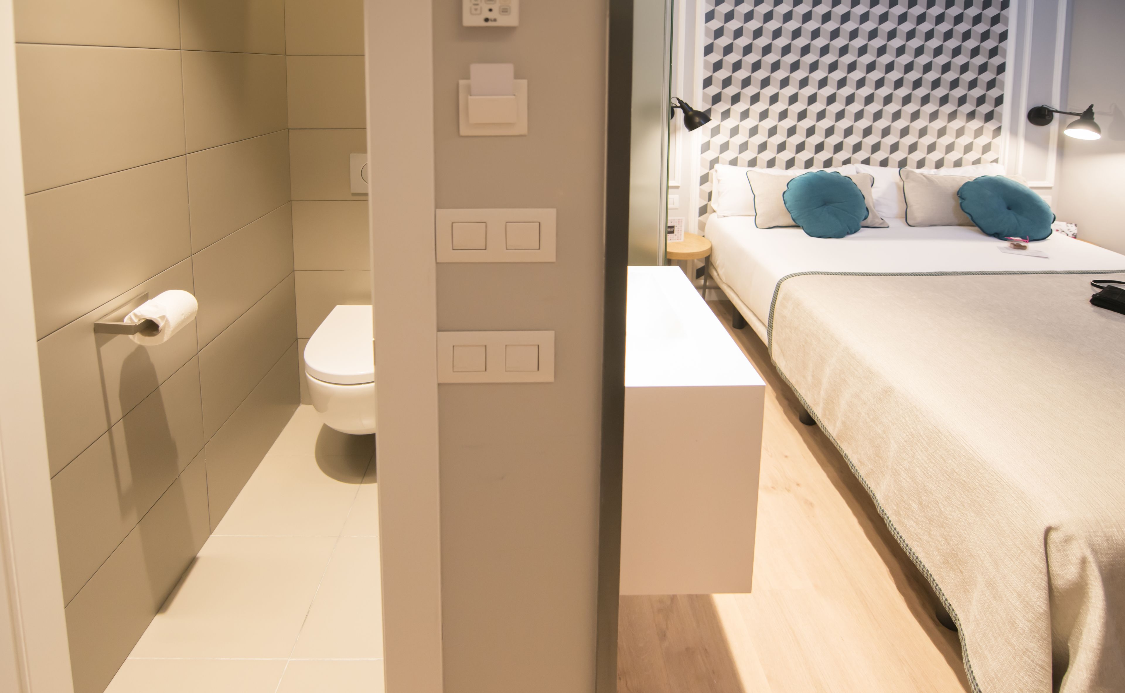 Een moderne badkamer met toilet, een zeepdispenser en een douchegedeelte.