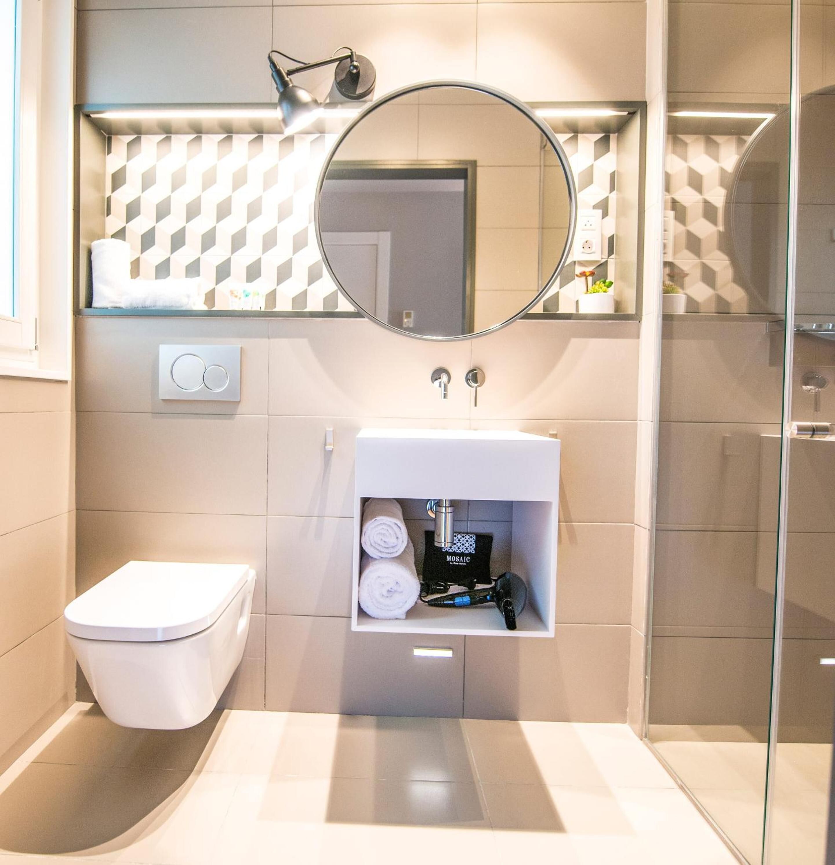 A modern bathroom with a toilet, a sink with a mirror above it, and a shower area.