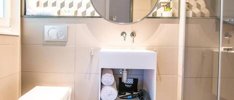 A modern bathroom with a toilet, a sink with a mirror above it, and a shower area.