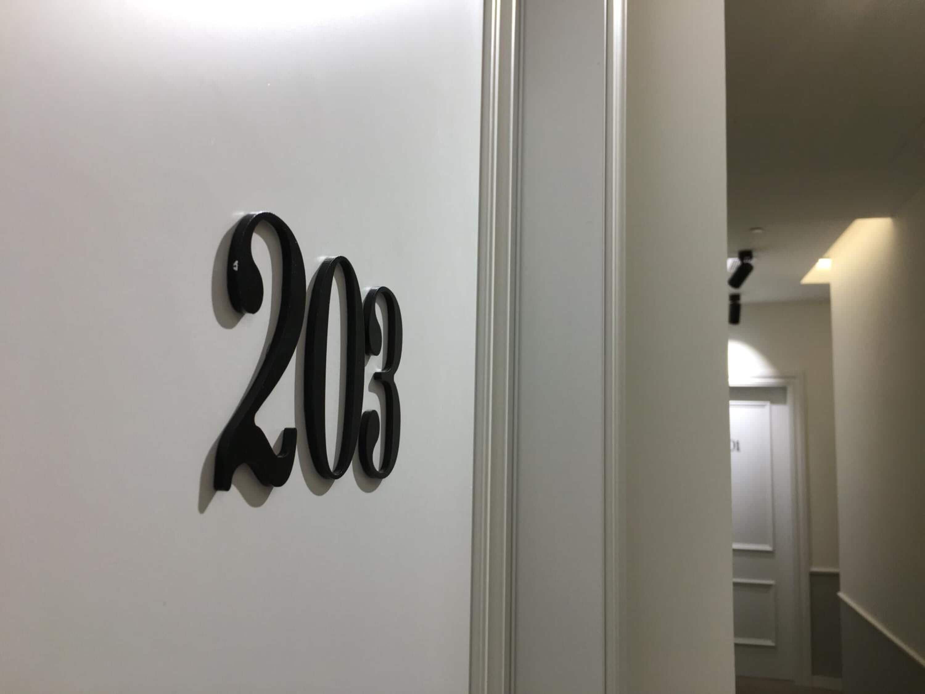 Pasillo con una pared blanca que muestra el número '203'.