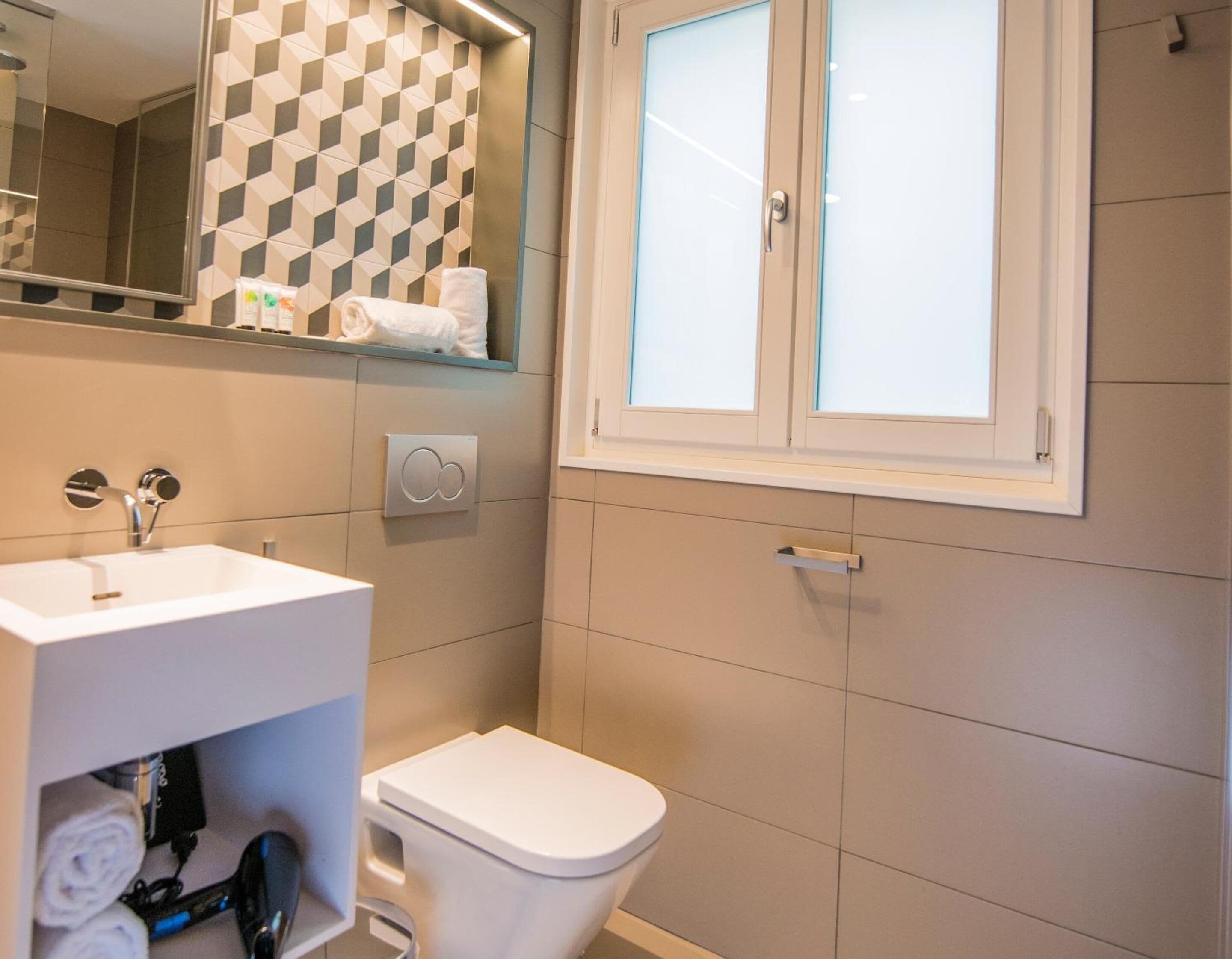A bathroom with a white sink, a toilet, and a mirror.