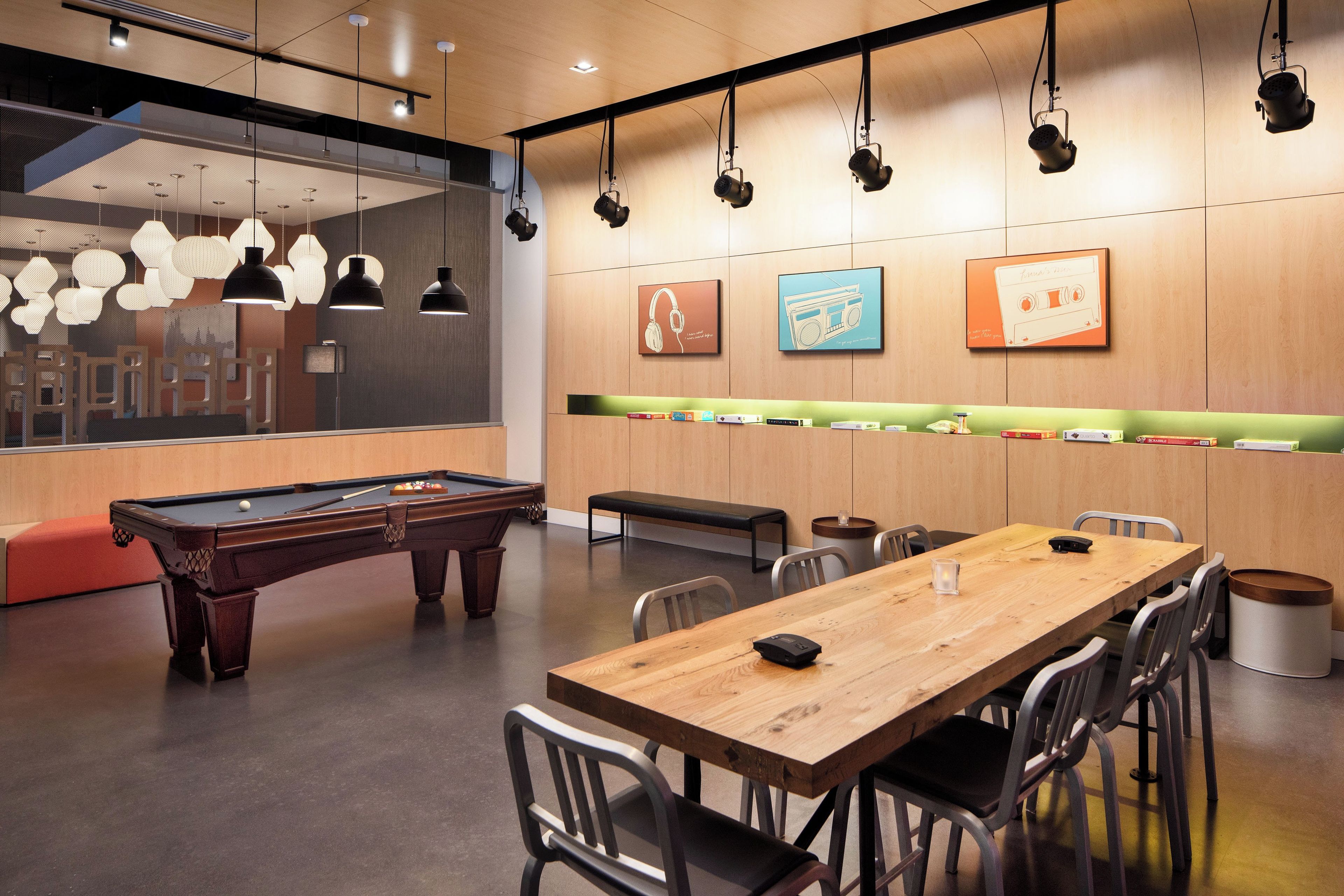 A modern lounge area with a pool table, seating, and artwork on the walls.
