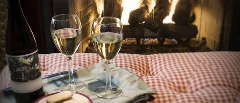 Un ambiente acogedor con un mantel a cuadros, dos copas de vino blanco, una botella de vino y un plato con galletas.