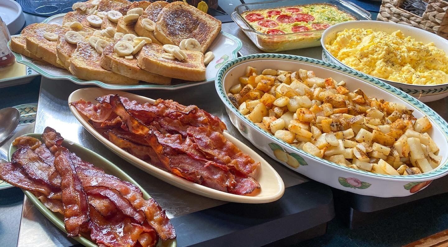 Un buffet della colazione con pane tostato, pancetta, patate e un piatto al forno.