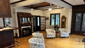 Un salon spacieux doté d’une cheminée, de parquet et de fauteuils à motifs.