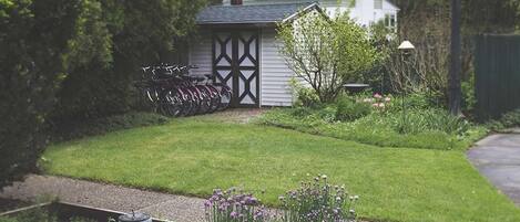 Ein Garten mit Gartenhaus, Fahrrädern und einem Weg zum Haus.