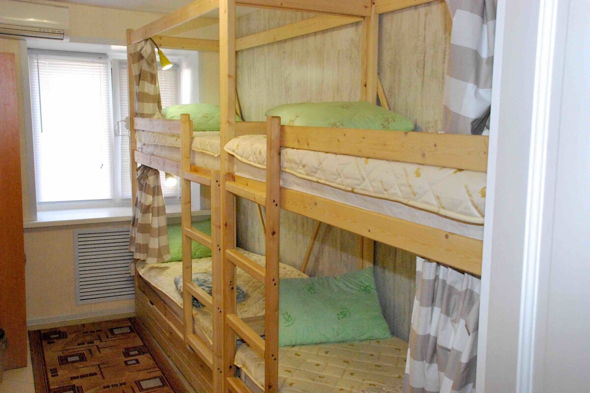 A bunk bed room with a window, a radiator, and a patterned rug.