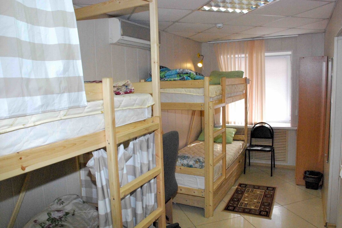 A dormitory room with bunk beds, a desk, and a chair.