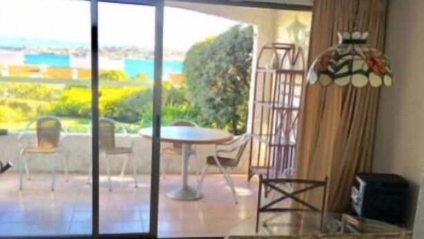 A room with a balcony, a table, chairs, and a hanging lamp. - Departamento Puerto Velero Angelica (Coquimbo)
