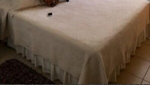 A hotel room with a large bed, a framed picture on the wall, a bedside table with a lamp, and a window with curtains. - Departamento Puerto Velero Angelica (Coquimbo)