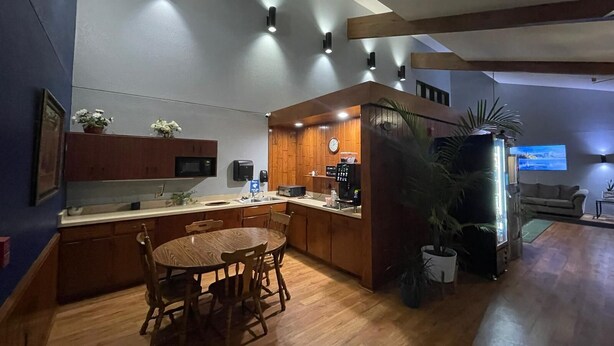 A modern kitchen with wooden cabinets, a dining table, and a coffee machine.