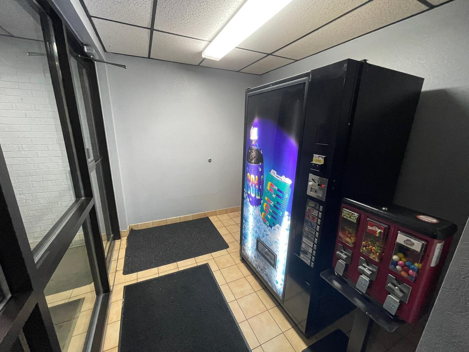 A room with a vending machine, a door, and a wall with a window.