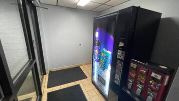 A room with a vending machine, a door, and a wall with a window.