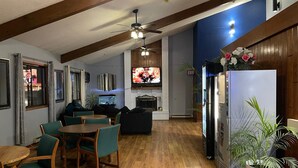 A spacious living area with wooden flooring, a dining set, a TV, and a refrigerator.