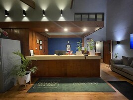 Un área de recepción con un mostrador de madera, una pared azul y un tapete de bienvenida.
