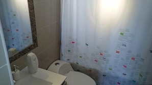 A bathroom with a toilet, sink, and mirror.