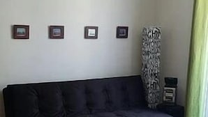 Un soggiorno con un divano scuro, un tavolino rotondo in legno e una tenda decorata.