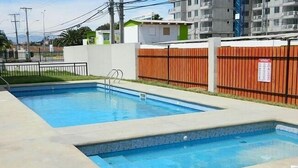 Una piscina rettangolare con una scala in metallo e una recinzione in legno.