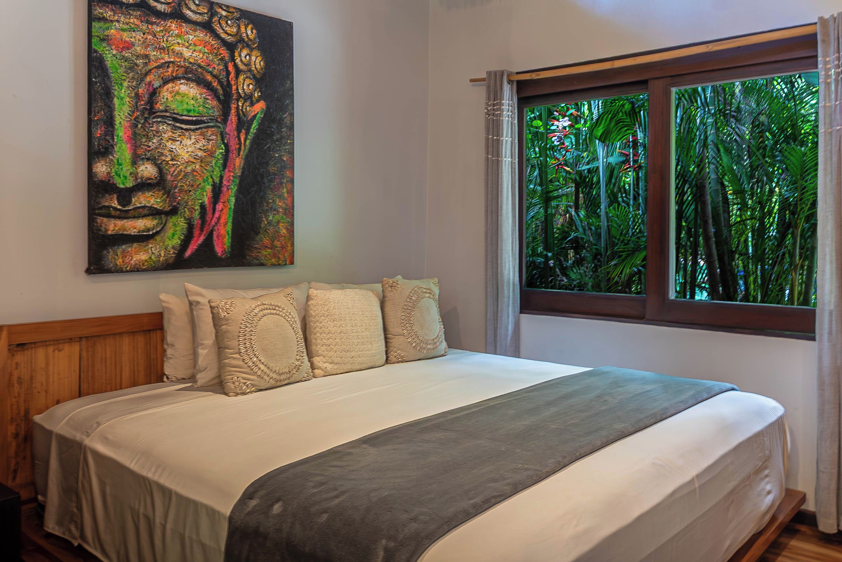 Un dormitorio con una cama grande, una ventana con vista a zonas verdes y un cuadro en la pared.