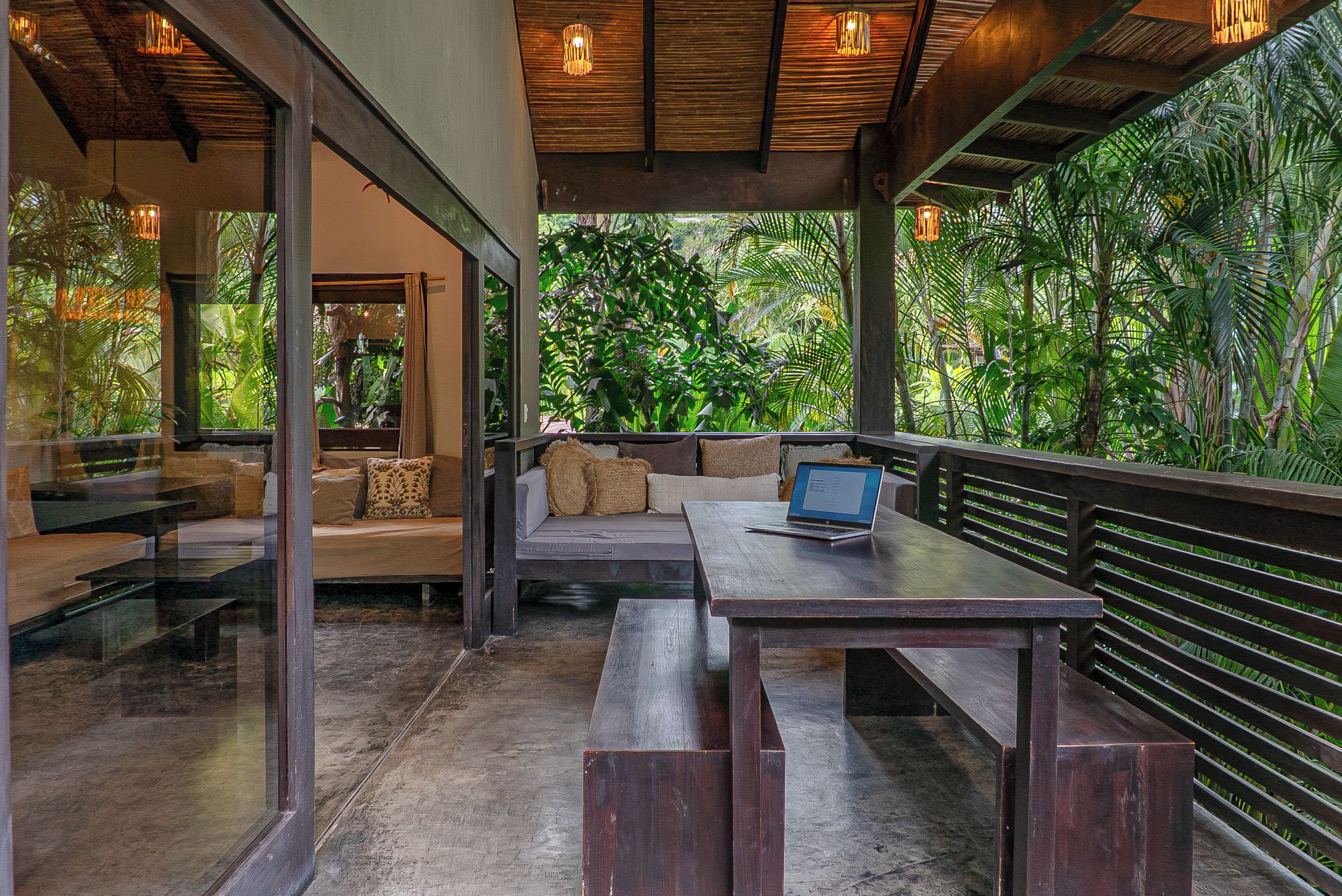 An outdoor seating area with a table and benches, surrounded by lush greenery.