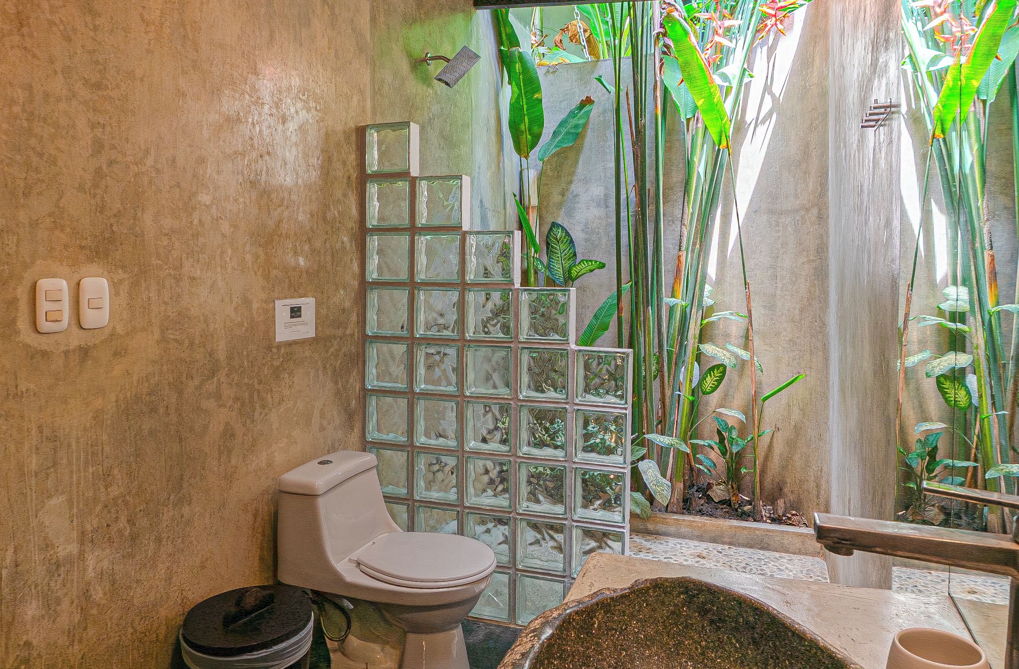 A bathroom with a toilet, a glass shower enclosure, and a sink with a decorative basin.
