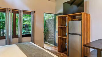 Quarto com cama, guarda-roupa de madeira, frigorífico e janela com cortinas.
