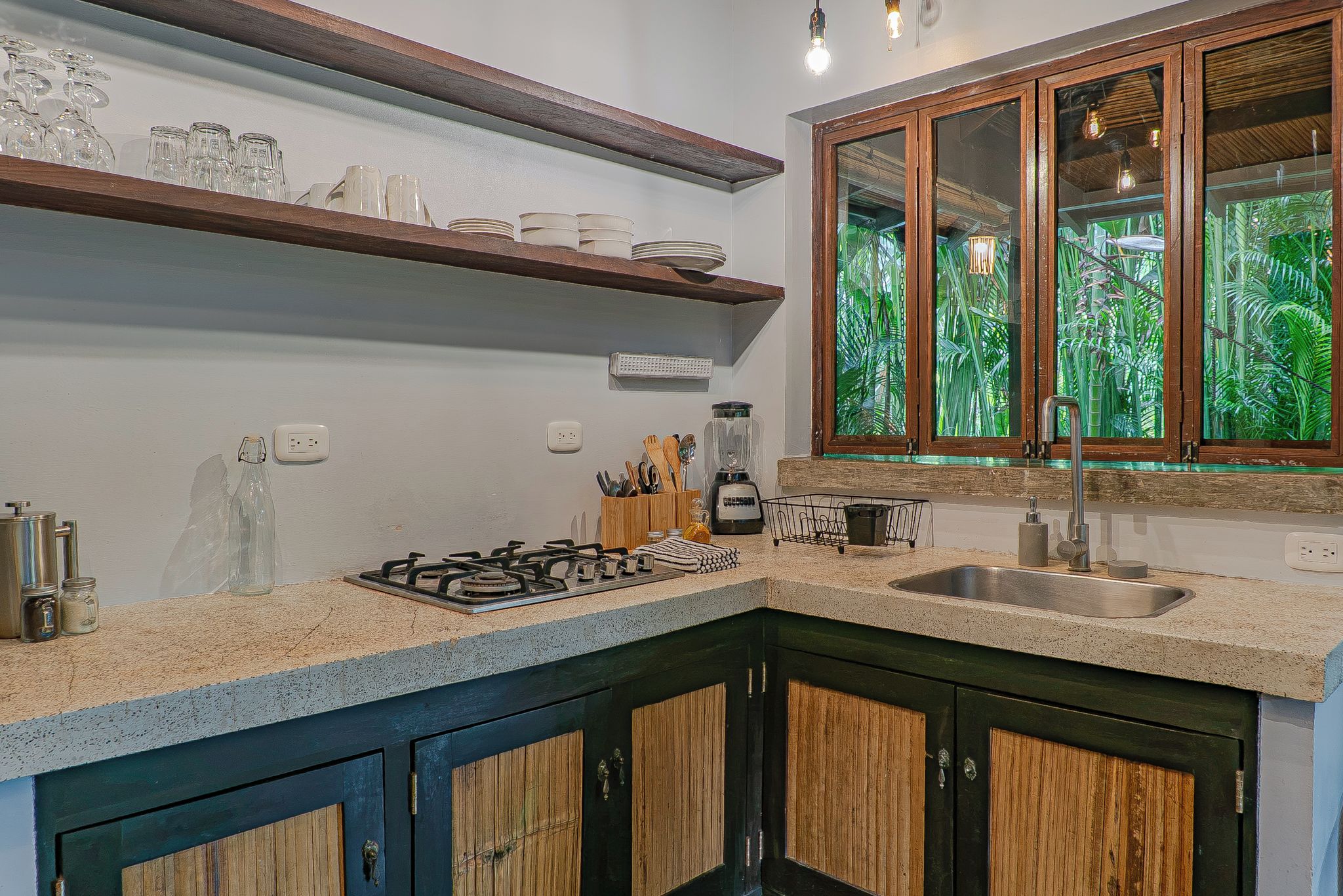 Una cocina con estufa a gas, un lavamanos y una ventana con vistas a follaje.