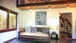 A room with a wooden sofa, a wall-mounted Buddha statue, and a staircase. - Lua Villas (Cóbano)