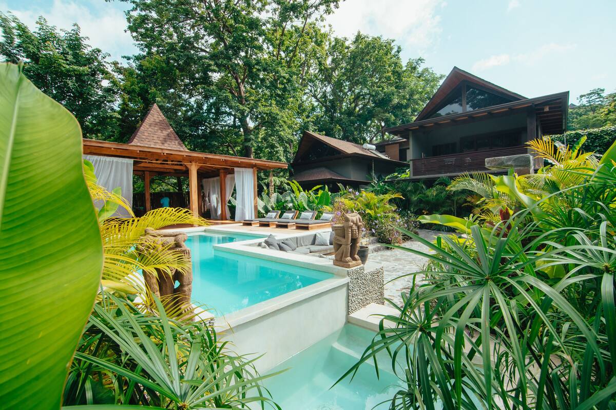 A pool area with a gazebo, lounge chairs, and a statue.