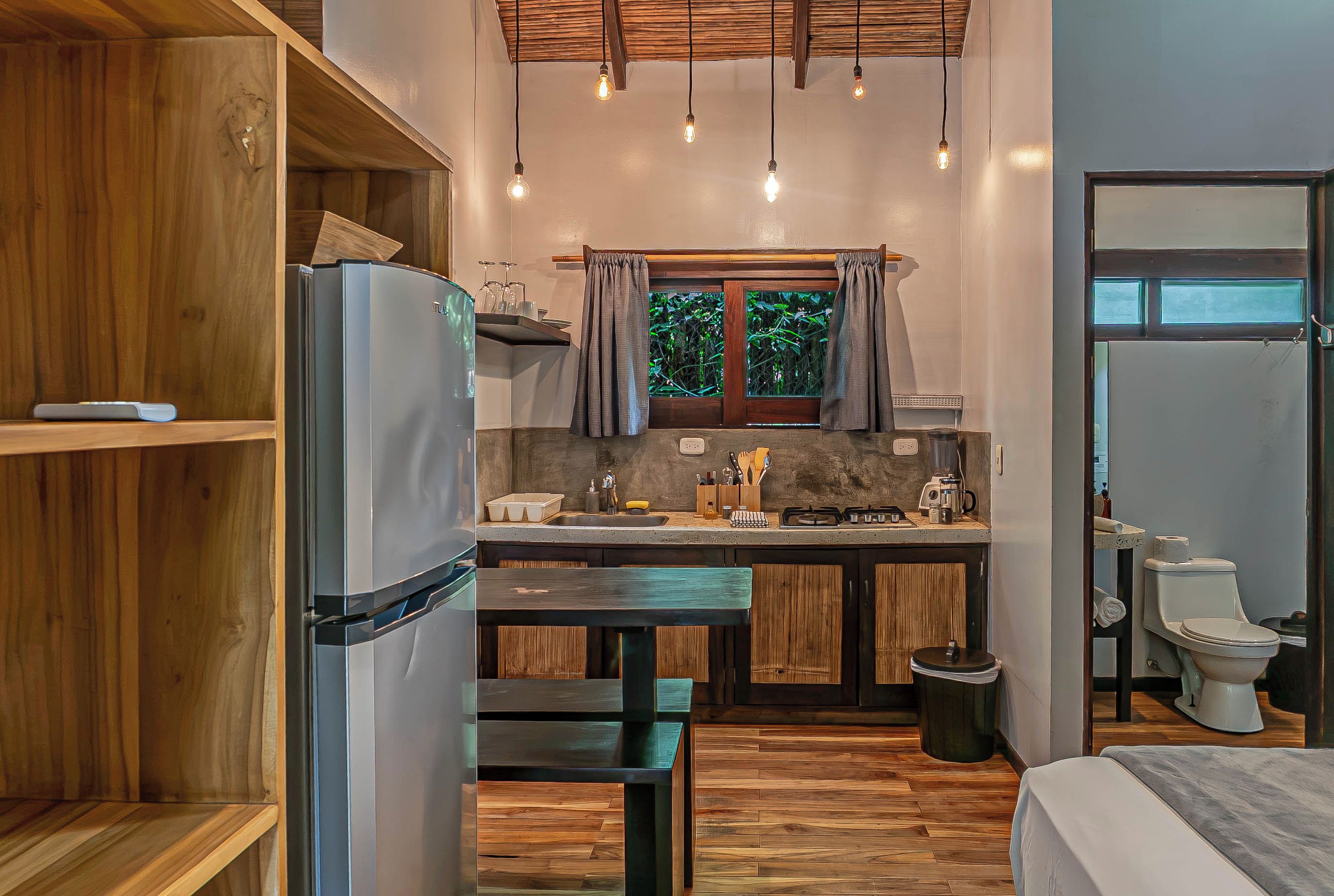 A compact kitchen with a refrigerator, sink, and window.