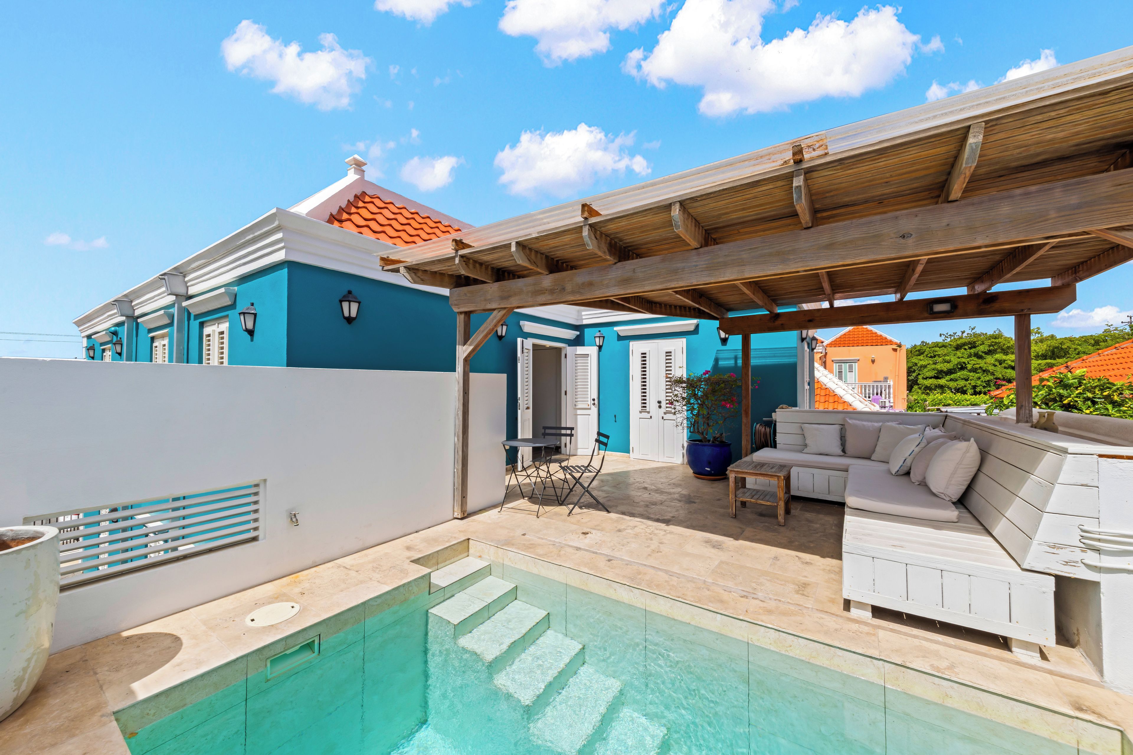 Een woonhuis met zwembad, buitenmeubilair en een overdekt terras.