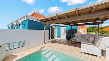 Een woonhuis met zwembad, buitenmeubilair en een overdekt terras.