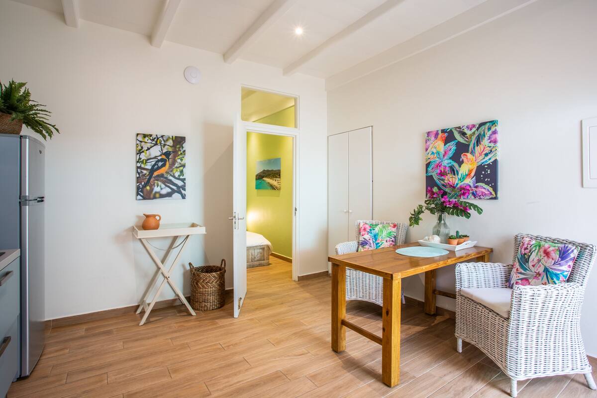 Una sala de estar moderna con una mesa de comedor de madera, sillas de mimbre y obras de arte en las paredes.