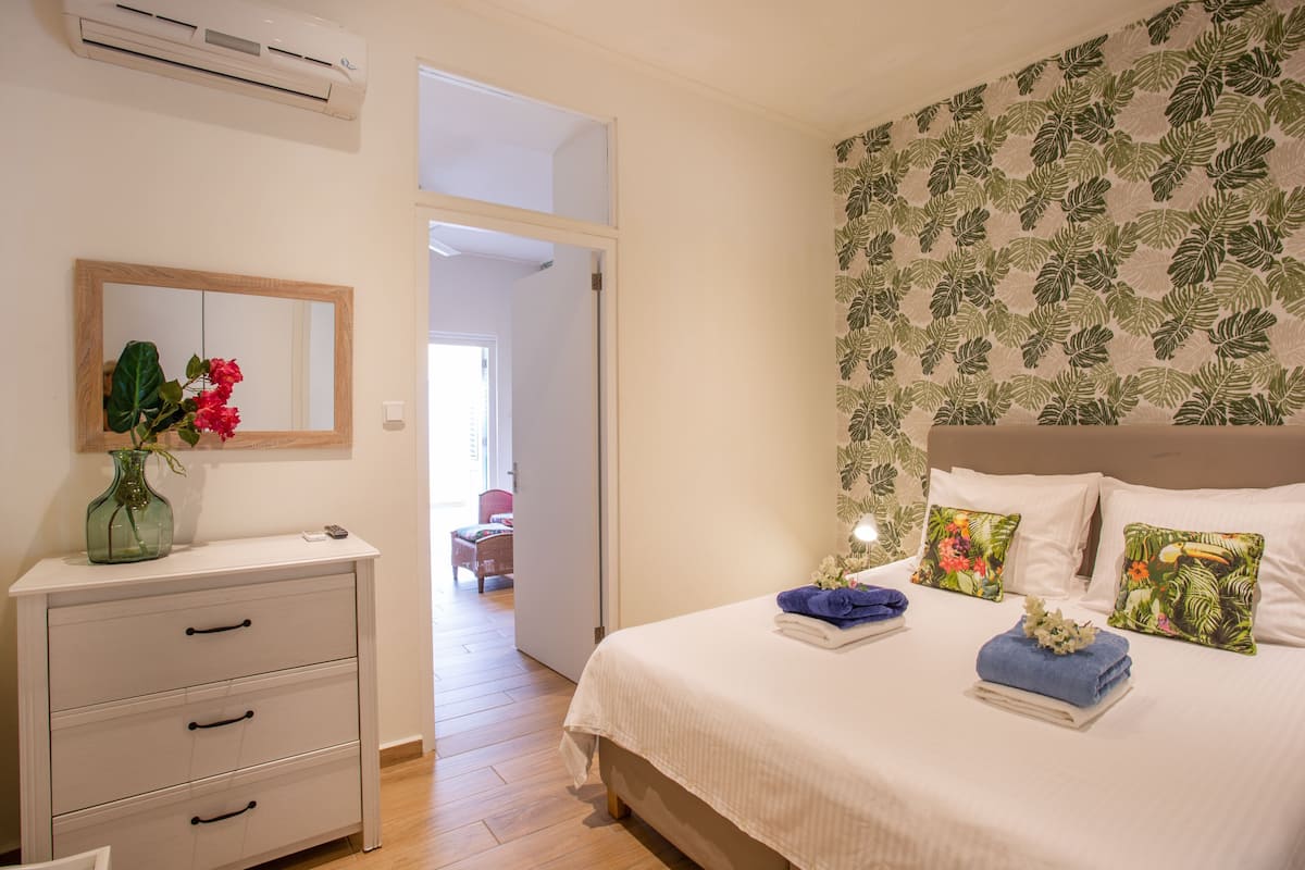 Un dormitorio con cama, cómoda, espejo y puerta que da a otra habitación.