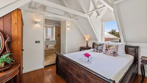Et soveværelse med en træseng, hvide vægge og et skråt loft.
