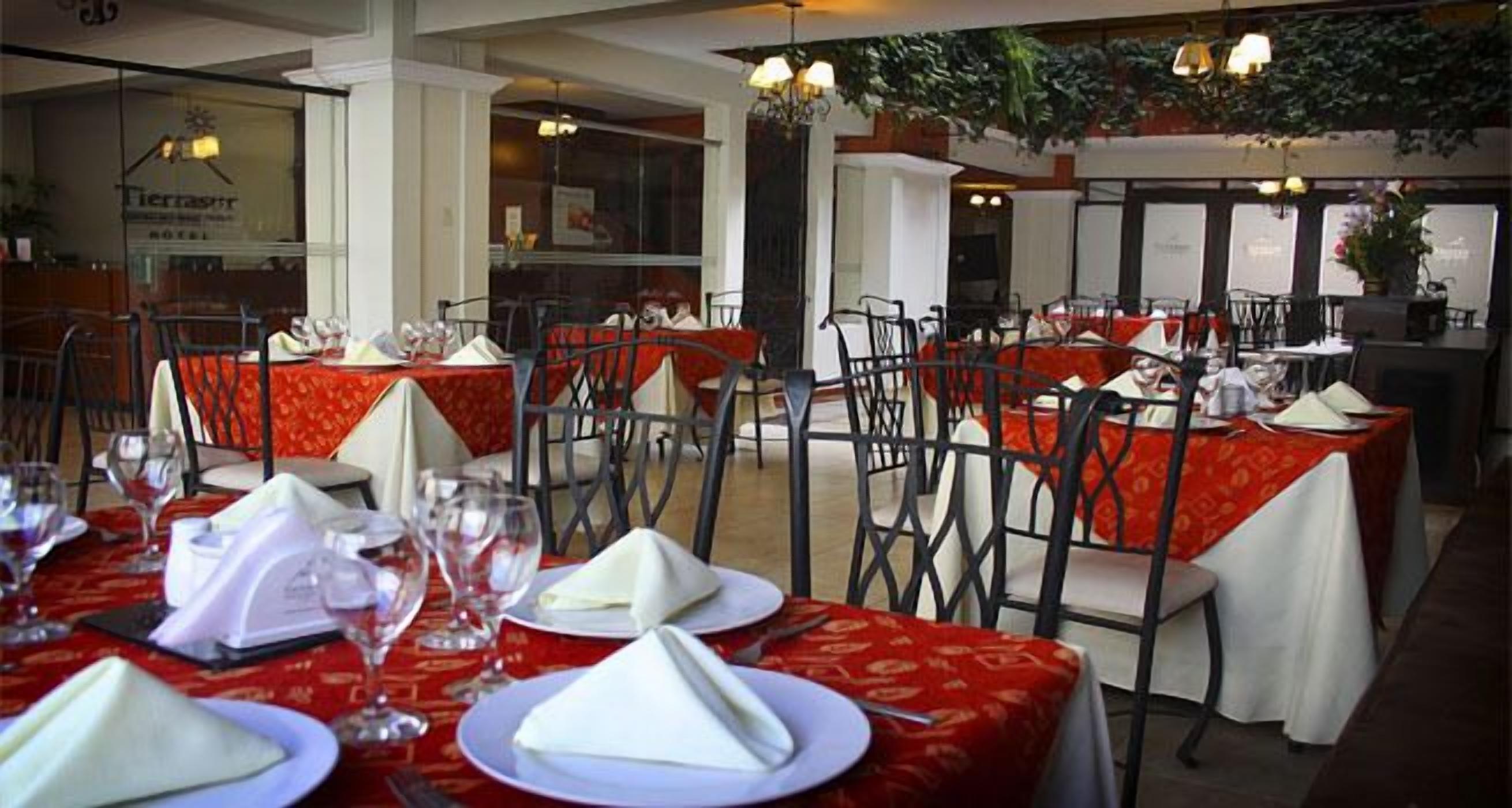 Un restaurante con mesas dispuestas para comer, con manteles rojos y servilletas blancas.