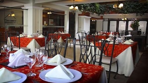 Un restaurant où les tables sont dressées pour le service, avec des nappes rouges et des serviettes blanches.