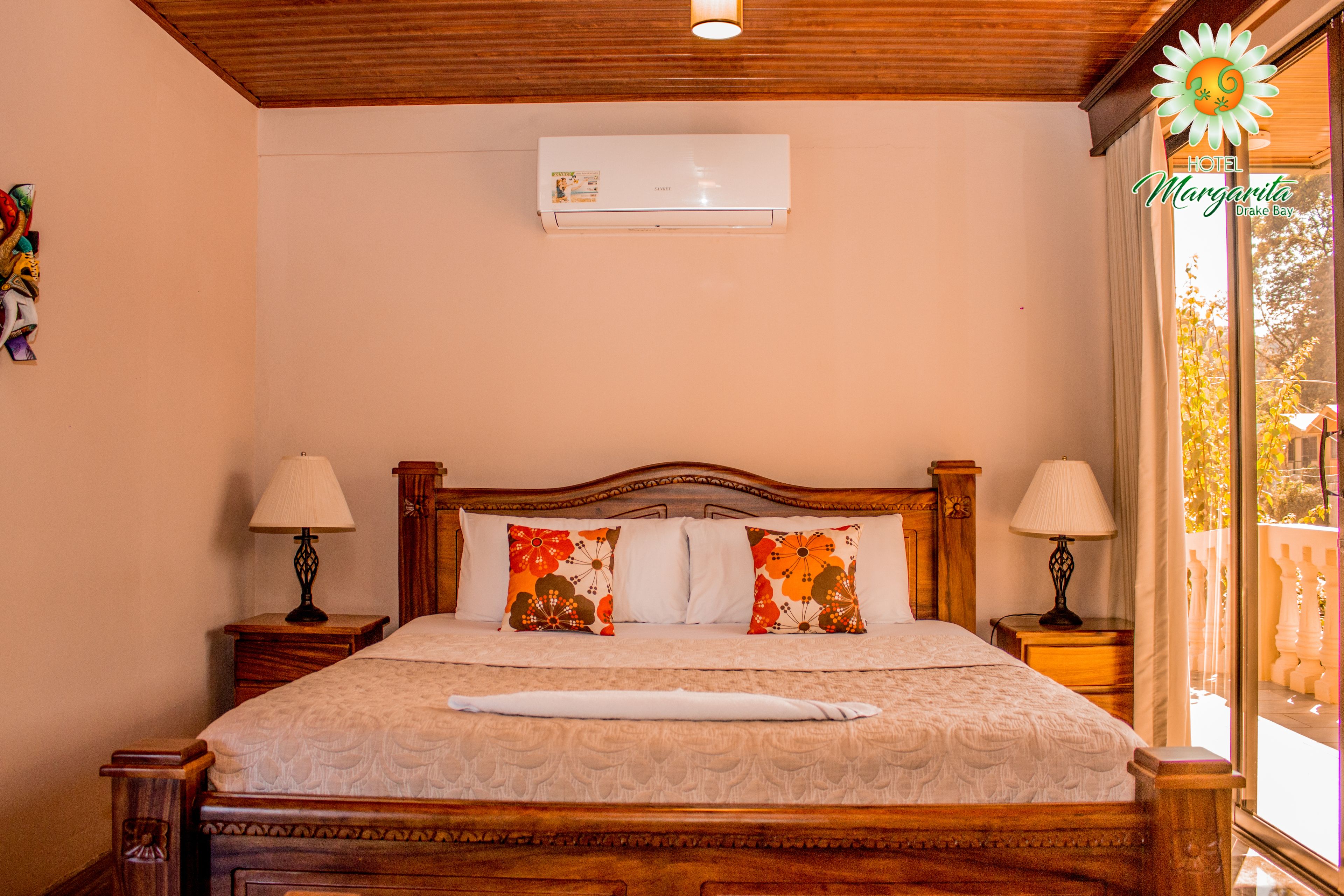 A neatly made bed with floral pillows, wooden headboard, and bedside lamps.