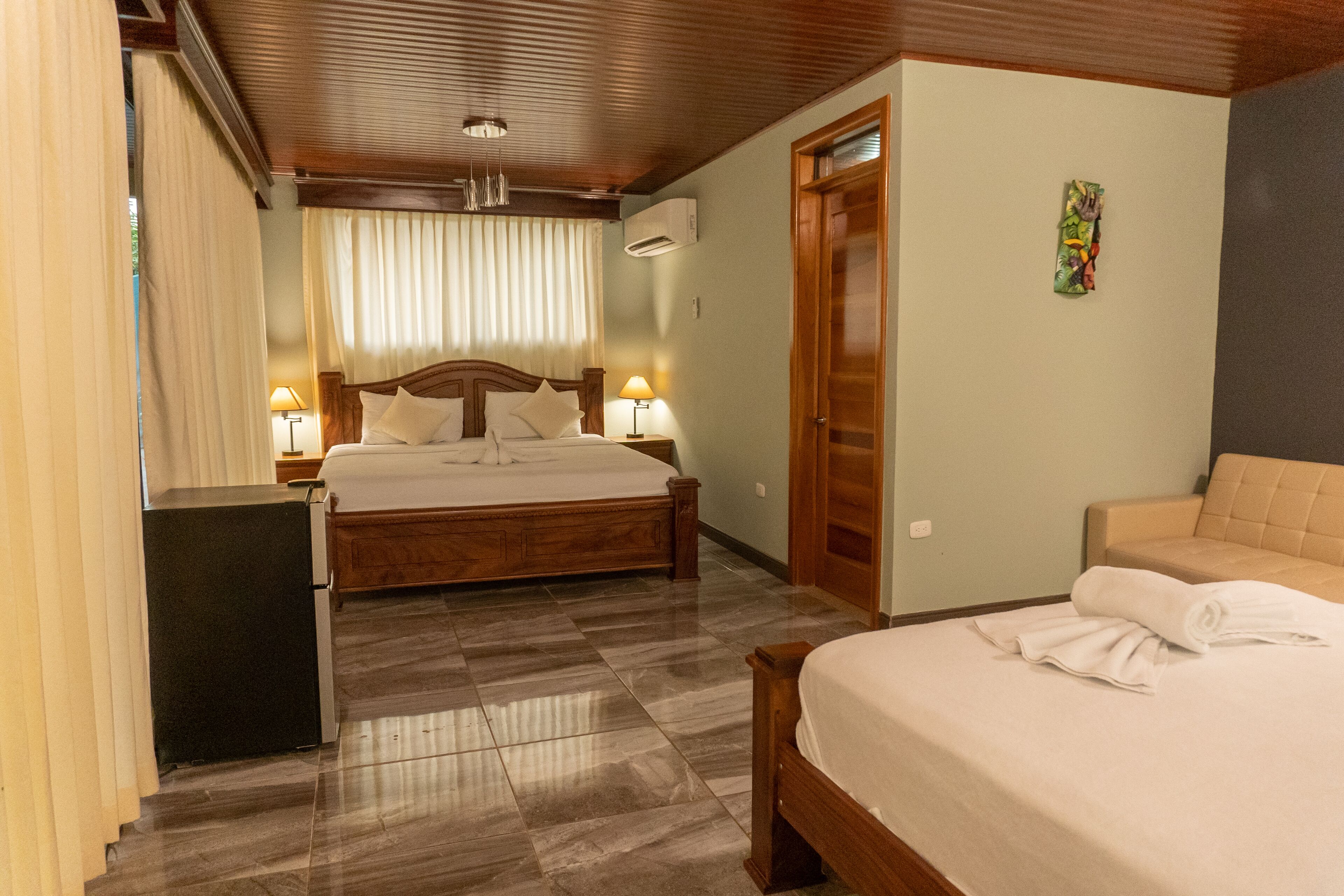 Habitació d'hotel amb un llit gran, una taula de nit amb làmpades, un escriptori petit i un sofà.