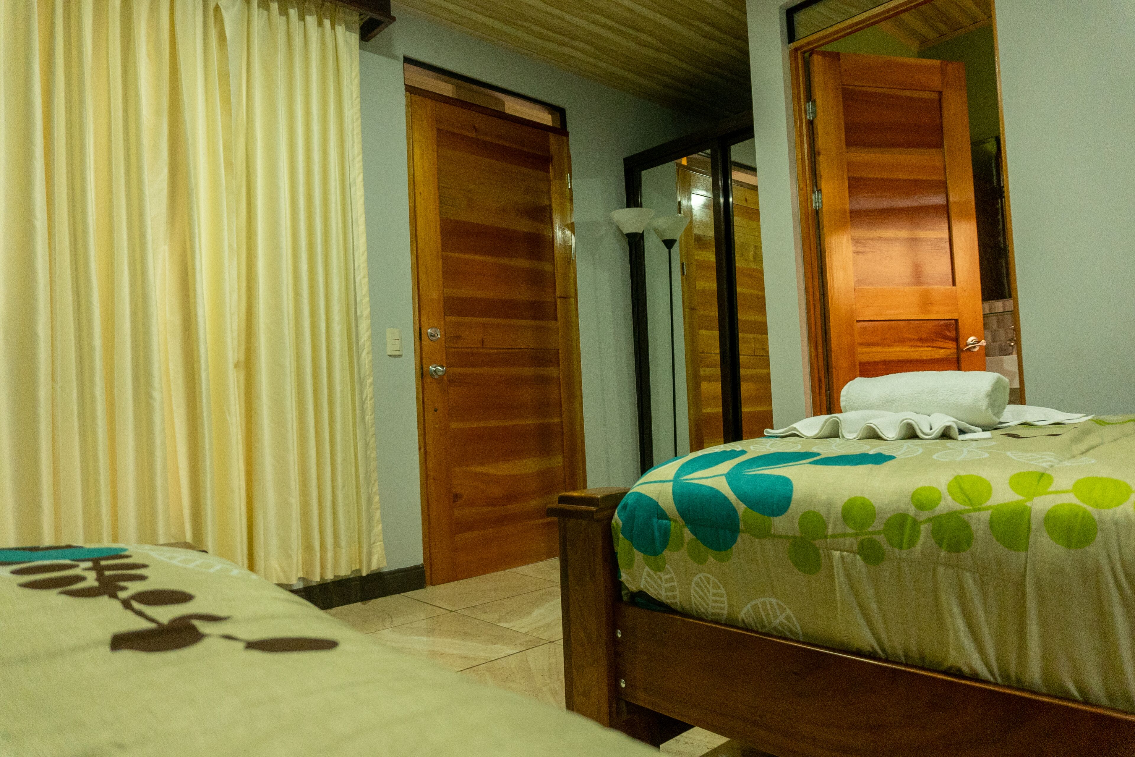 Une chambre d’hôtel avec un lit, une porte en bois et un miroir.