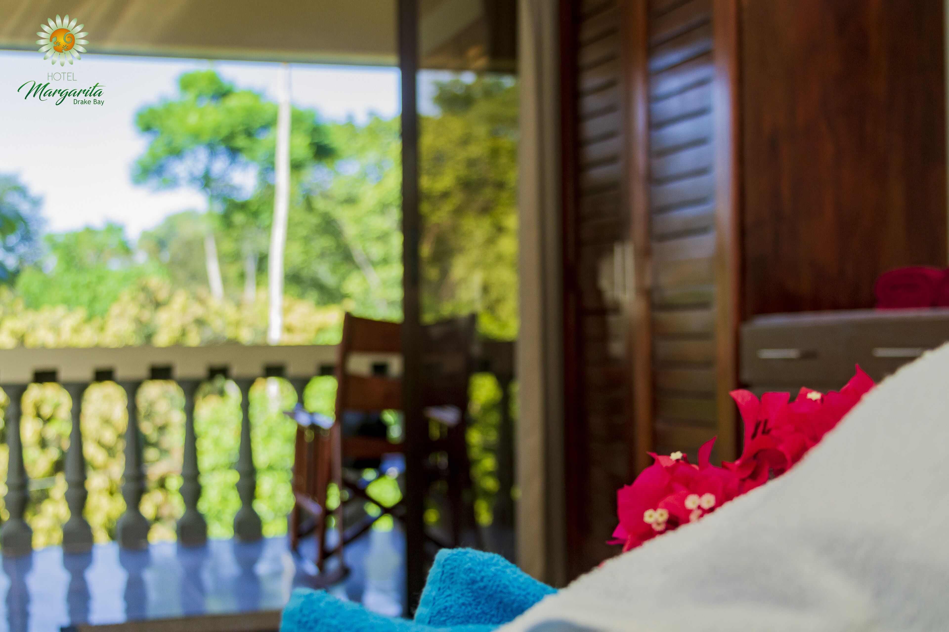 A hotel room with a view of greenery and a wooden railing.