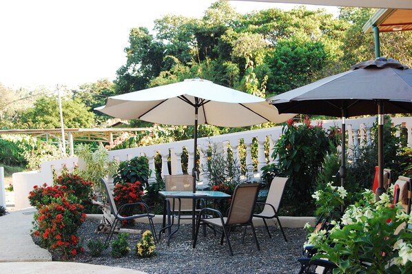 An outdoor patio with two umbrellas, a table, and chairs. - Hotel Margarita (Drake Bay)