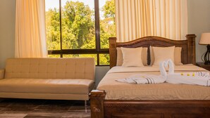 A hotel room with a bed, a sofa, and a large window with curtains. - Hotel Margarita (Drake Bay)