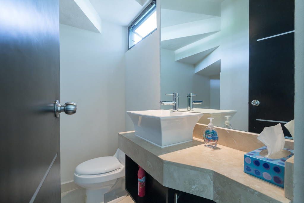 A modern bathroom with a white sink, a mirror, and a toilet.