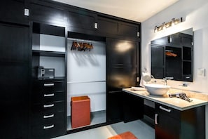 A modern bathroom with a black vanity, a large mirror, and a white sink.