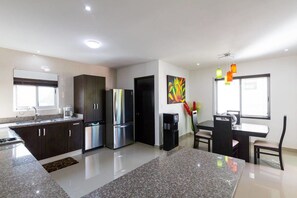 A modern kitchen with dark cabinets, stainless steel appliances, and a granite countertop. - Awah by CocoBR (Playa del Carmen)