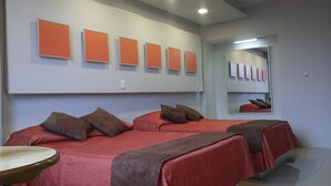 Habitación de hotel con dos camas, una mesa redonda y un espejo.
