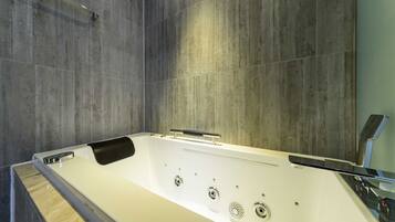 A modern bathroom with a freestanding bathtub, a wooden bench, and a large mirror.
